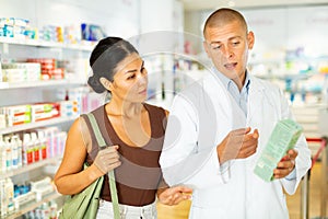 Pharmacist advises customer in harmacy, offers medicine for body care