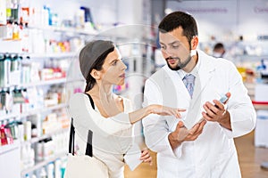 Pharmacist advises customer in pharmacy, offers medicine for body care