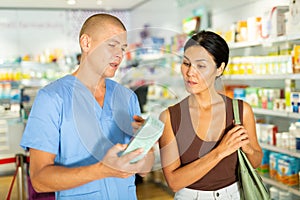 Pharmacist advises customer in a pharmacy, offers medicine for body care closeup