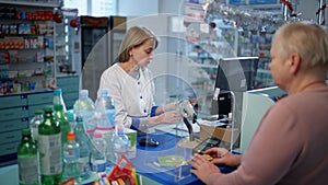 A pharmacist advises an elderly woman at the checkout.