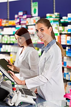 Pharmacist with assistant in pharmacy