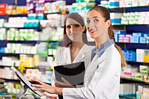 Pharmacist with assistant in pharmacy