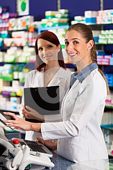 Pharmacist with assistant in pharmacy