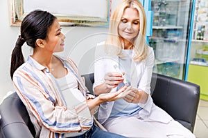 pharmacist checking glucose level to smiling pregnant woman