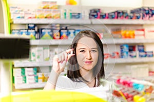 Pharmacist chemist woman show a pill. Pharmacy drugstore is background. Pretty, young laborant.