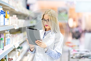 Pharmacist chemist woman standing in pharmacy drugstore, smiling and using tablet