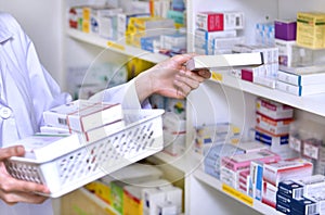 Pharmacist chemist woman standing refills the shelves with new stocks in pharmacy