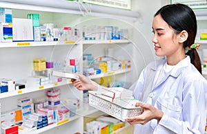 Pharmacist chemist woman standing refills the shelves with new stocks in pharmacy