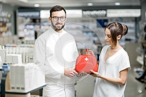 Pharmacist with client and first aid kit in the pharmacy