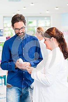 Pharmacist or drug store sales woman advising customer
