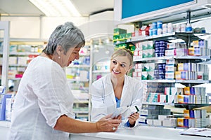 Pharmacist explaining medicine to a woman in the pharmacy for pharmaceutical healthcare prescription. Medical, counter