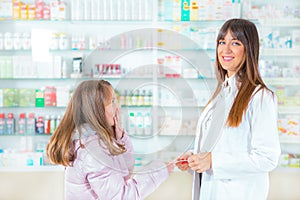 Pharmacist giving vitamins to child girl in drugstore