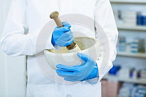 Pharmacist grinding medicine in mortal and pestle