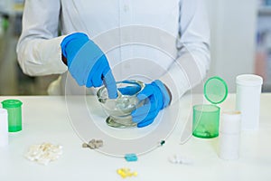 Pharmacist grinding medicine in mortal and pestle