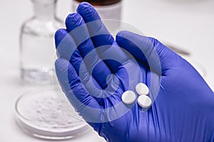 Pharmacist hand holding acetylsalicylic acid tablet, obtained by salicylic acid and acetic anhydride, known as aspirin