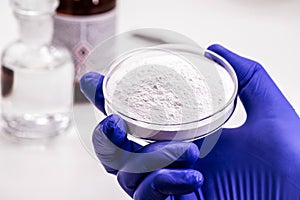 Pharmacist hand holding petri dish with acetylsalicylic acid, obtained by salicylic acid and acetic anhydride, known as aspirin