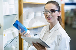 Pharmacist holding digital tablet while checking medicine in pharmacy