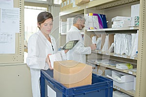 Pharmacist holding digital tablet in pharmacy stockroom