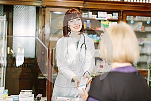 Pharmacist holding medicine box talking to customer in the pharmacy