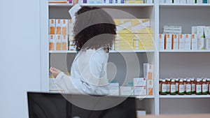 Pharmacist holding, showing and talking about medicine to female customer in a pharmacy. Medical professional discussing