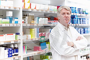 Pharmacist near medical store. Portrait of mature pharmacist standing near shelf at medical store.