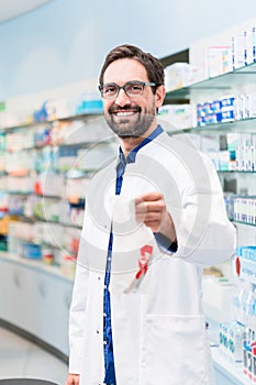 Pharmacist in pharmacy selling pharmaceuticals in bag