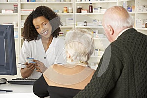 Pharmacist in pharmacy with senior couple