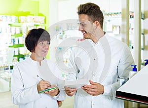 Pharmacist and pharmacy technician posing in drugstore