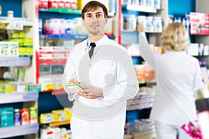 Pharmacist and pharmacy technician posing in drugstore