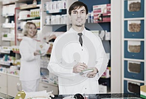 Pharmacist and pharmacy technician posing in drugstore