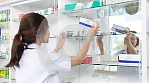 Pharmacist picks up pills on shelf from doctor`s prescription