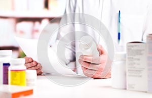 Pharmacist reading prescription with medicine and pill bottle