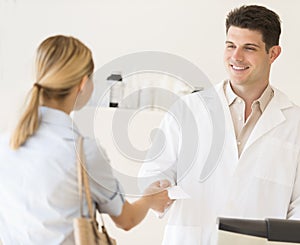 Pharmacist Receiving Prescription Paper From Customer At Store