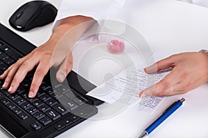 Pharmacist's hands typing on keyboard