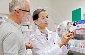 Pharmacist showing drug to senior man at pharmacy