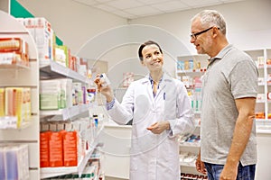 Pharmacist showing drug to senior man at pharmacy