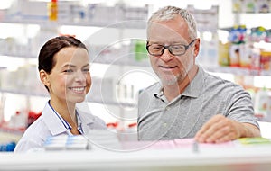 Pharmacist showing drug to senior man at pharmacy