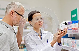 Pharmacist showing drug to senior man at pharmacy