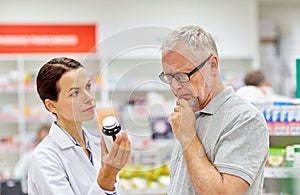 Pharmacist showing drug to senior man at pharmacy