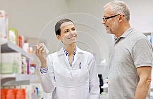 Pharmacist showing drug to senior man at pharmacy