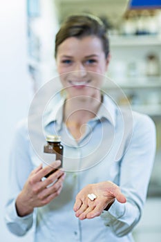 Pharmacist showing a medicine bottle and pills in pharmacy