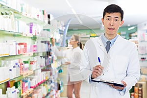 Pharmacist stocktaking medicines in drugstore