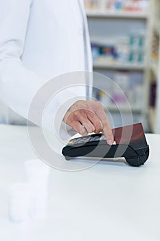 Pharmacist swiping card through payment terminal