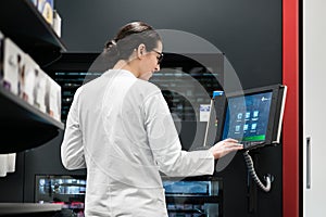 pharmacist using a computer while managing the drug stock in pha