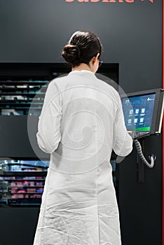 Pharmacist using a computer while managing the drug stock in pharmacy