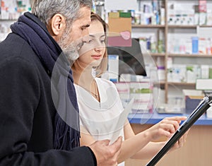 Pharmacist working in drugstore with customers.