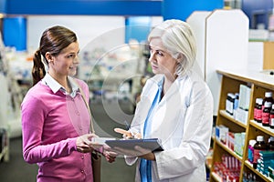 Pharmacist writing prescriptions for customer on clipboard