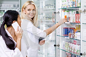 pharmacists using digital devices and smiling each other