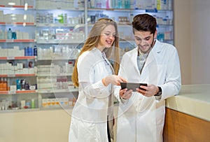 Pharmacists using digital tablet while checking medicine