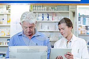 Pharmacists using digital tablet and computer